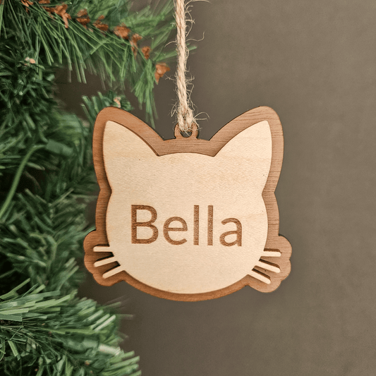 Personalized cat ornament hanging on a Christmas tree branch with engraved name Bella in layered wood design