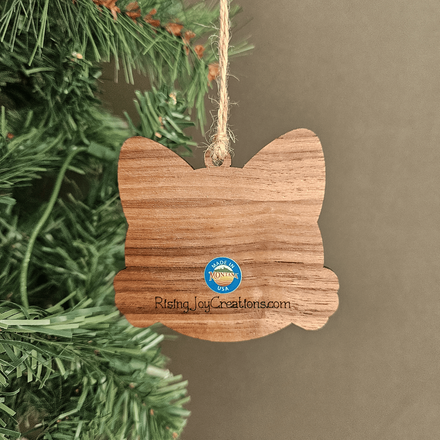 Wooden personalized cat ornament with engraved name Bella hanging from jute twine on a Christmas tree