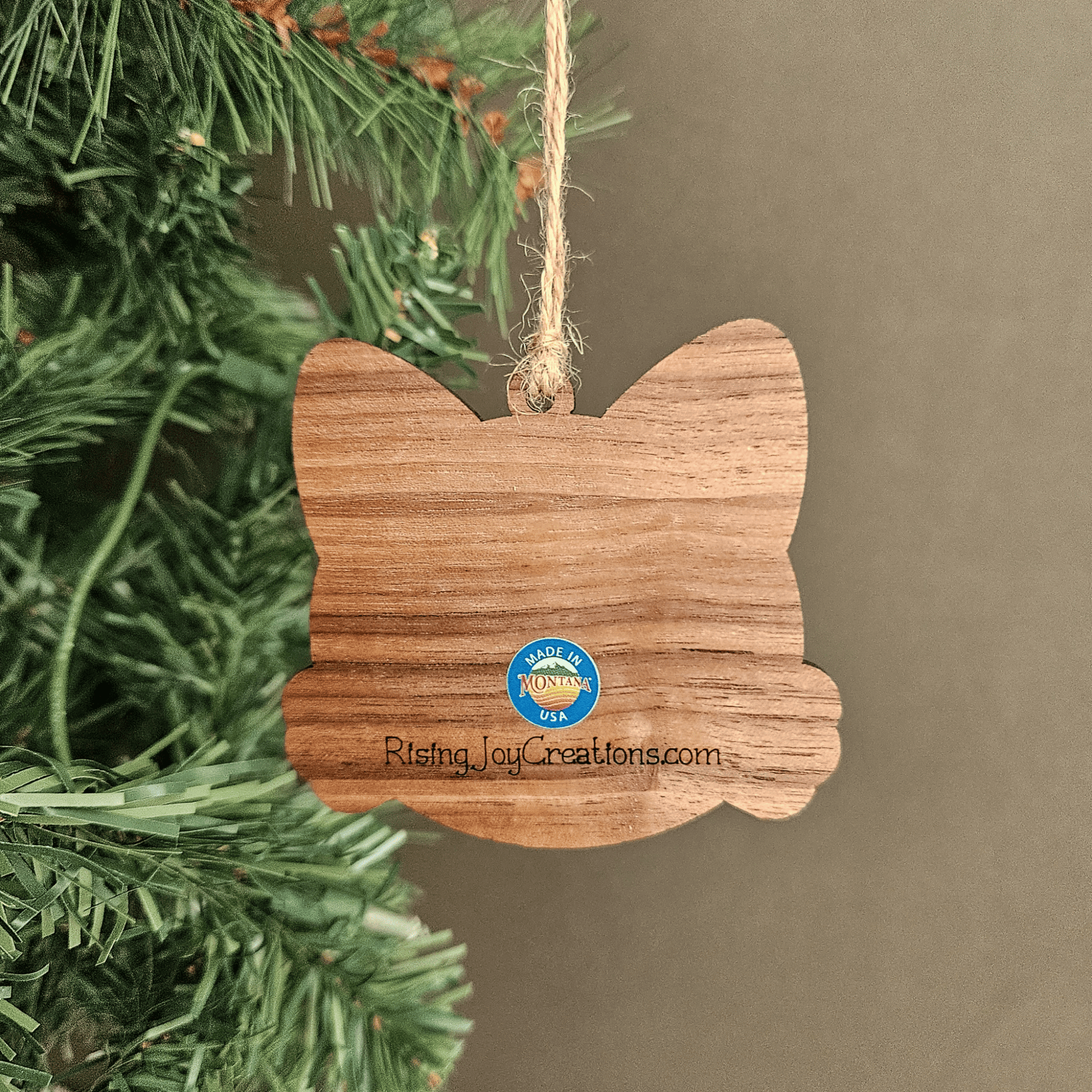 Wooden personalized cat ornament with engraved name Bella hanging from jute twine on a Christmas tree