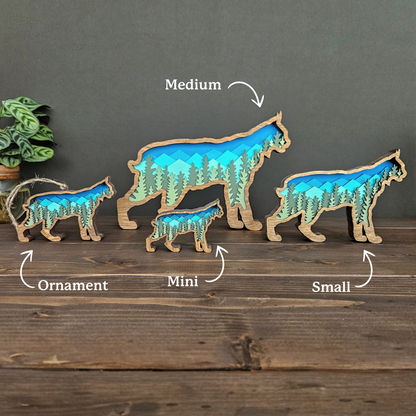 Set of four Bobcat or Lynx art pieces and ornament in different sizes on a wooden surface with a muted green background.