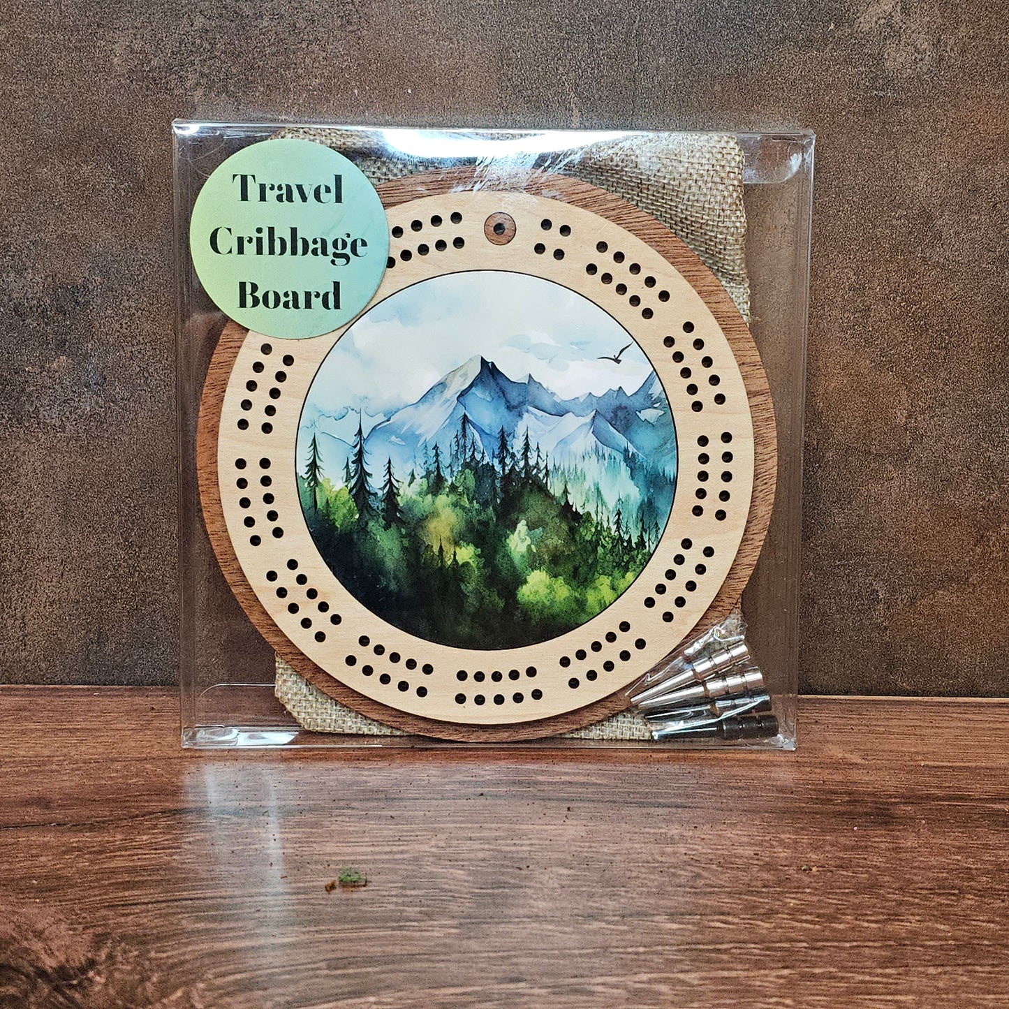 Travel cribbage board with scenic design on a wooden surface
