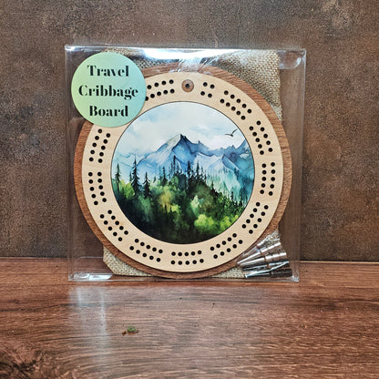 Travel cribbage board with scenic design on a wooden surface