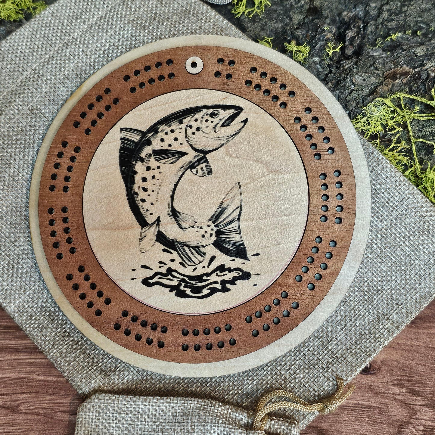 Wooden cribbage board with fish design on a textured surface