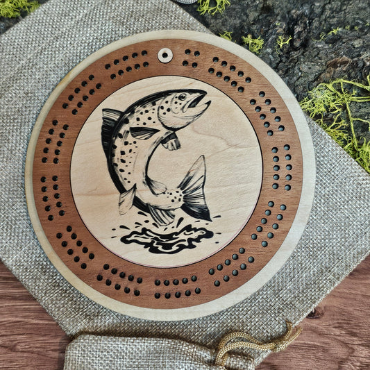 Wooden cribbage board with fish design on a textured surface