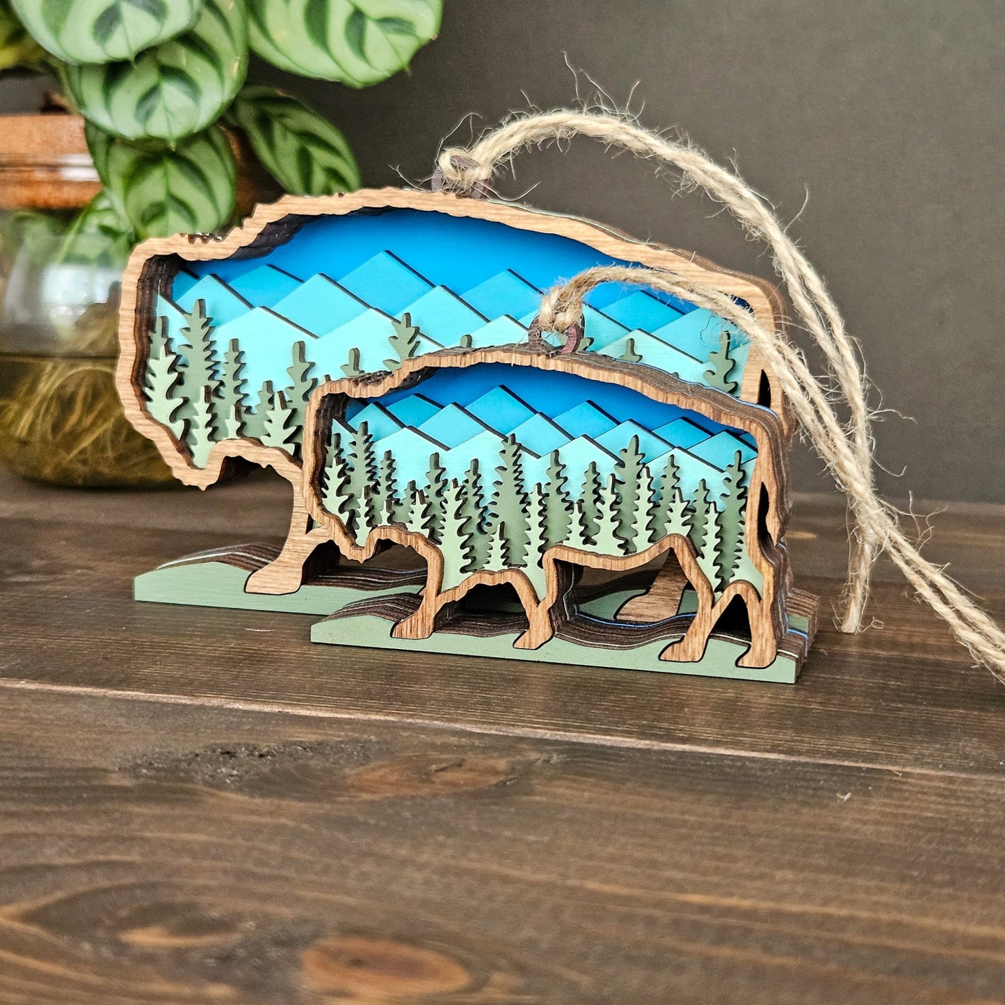 Wooden ornament shaped like a bear with a forest design on a wooden surface