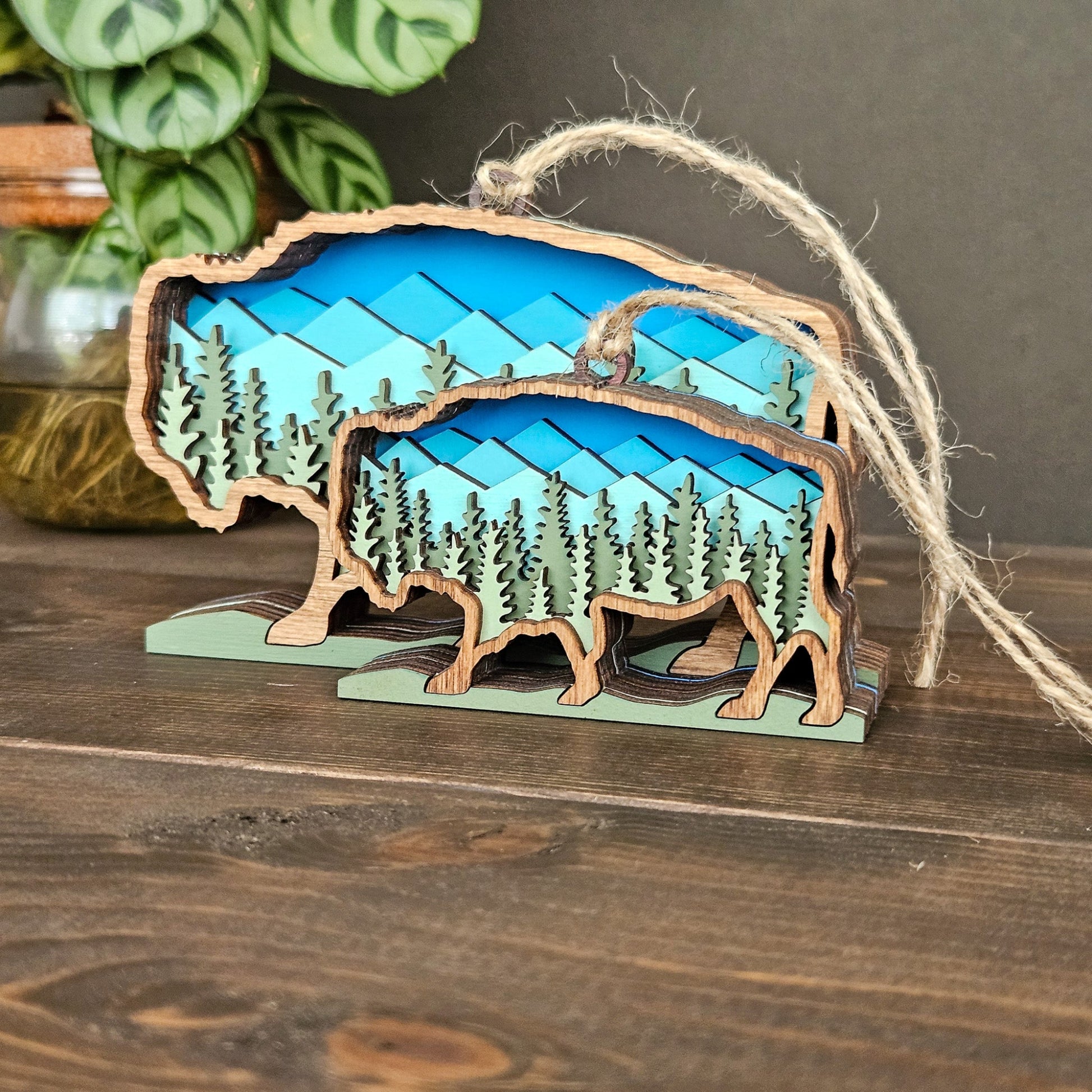 Wooden ornament shaped like a bear with a forest design on a wooden surface