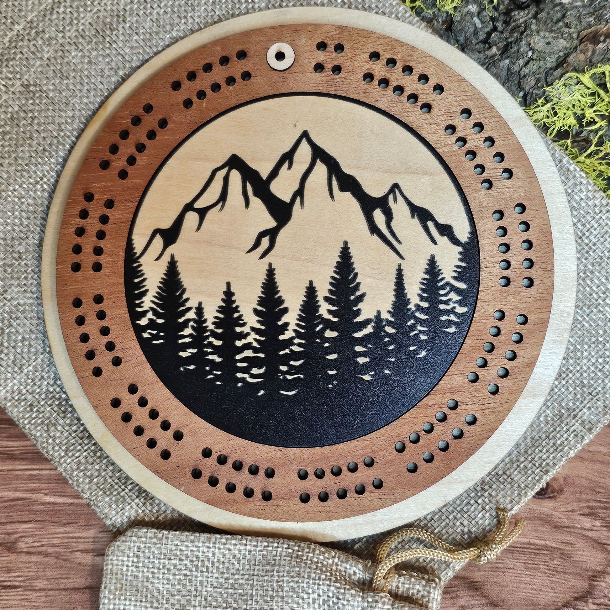 Wooden cirbbage board with nature-themed design on a textured surface