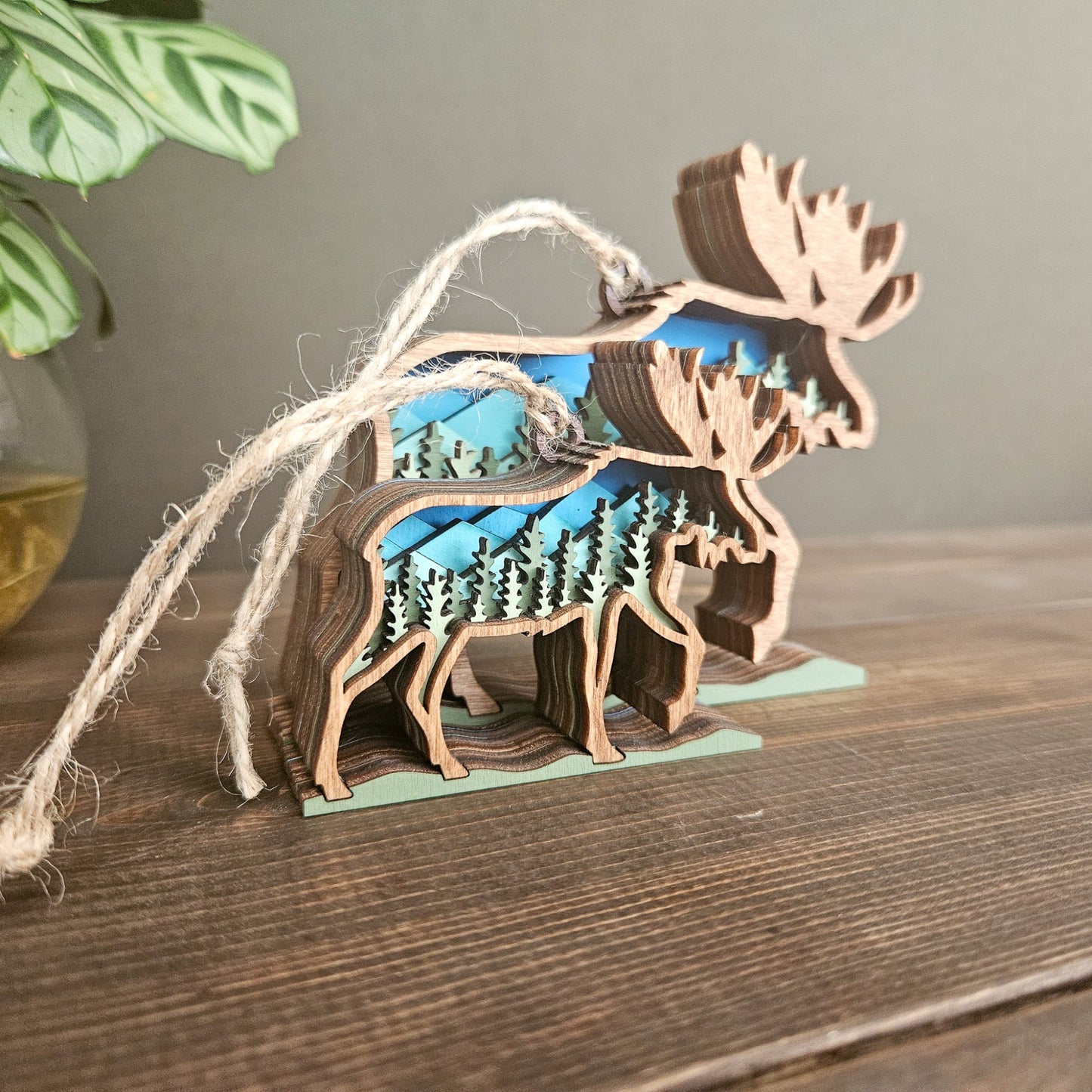 Wooden moose ornament with a landscape inside on a wooden surface