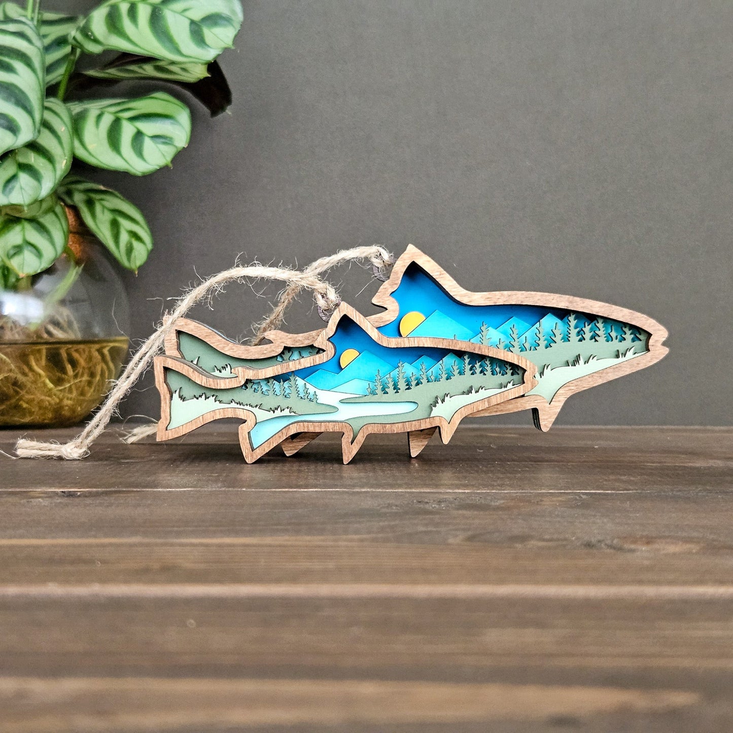 Wooden fish-shaped ornament with nature design on a wooden surface
