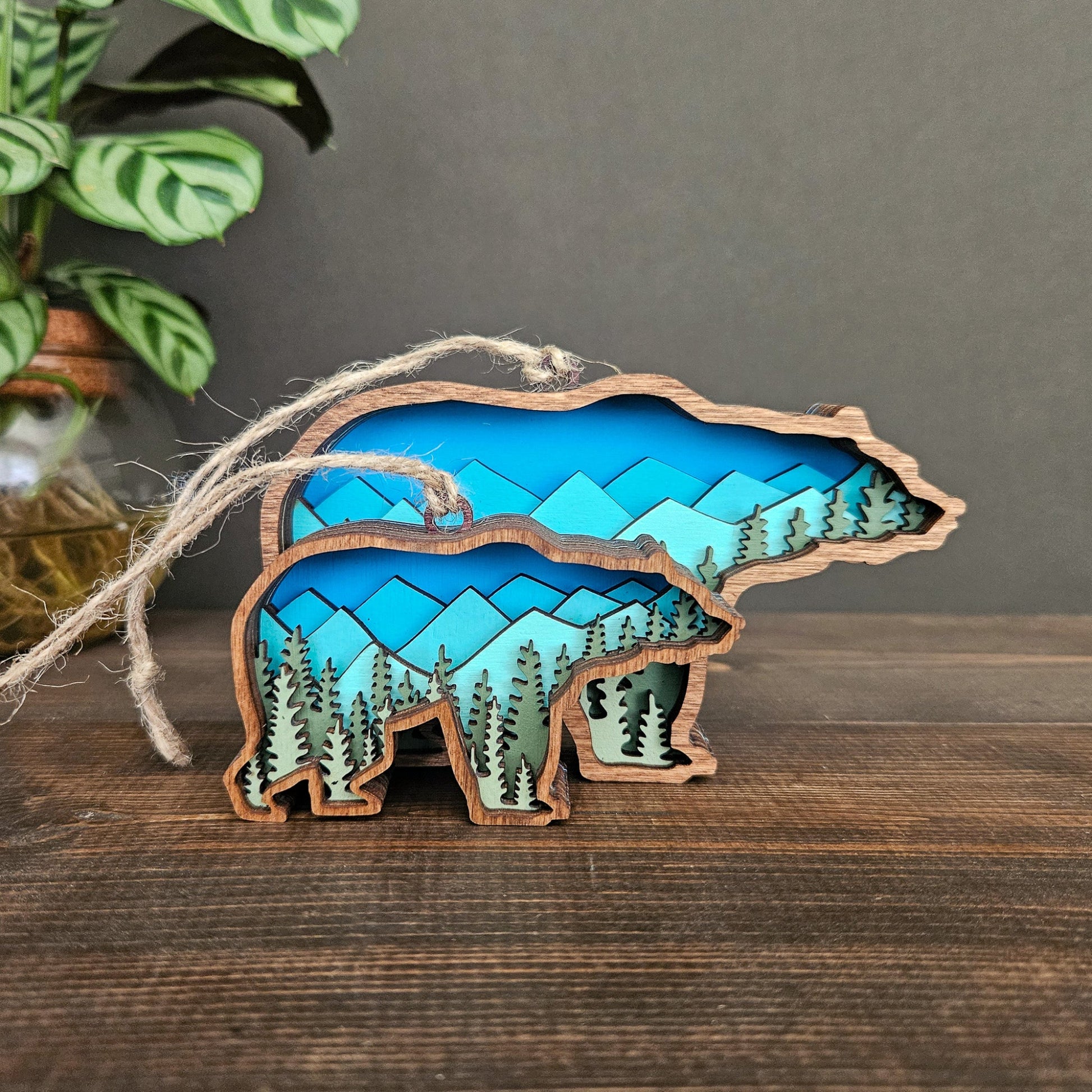 Wooden bear ornament with blue mountains design on a wooden surface