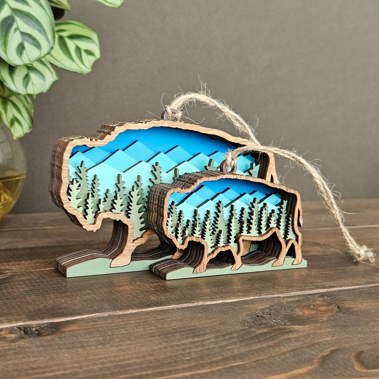 Wooden buffalo ornament with mountain and forest design on a wooden surface