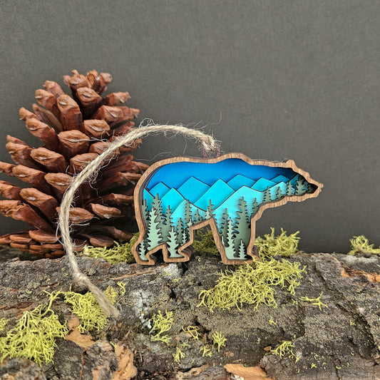 Wooden bear ornament with nature design on a branch with pine cone and moss