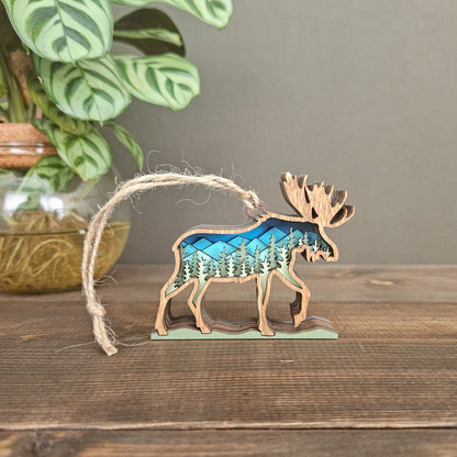 Decorative moose ornament with forest design on a wooden surface