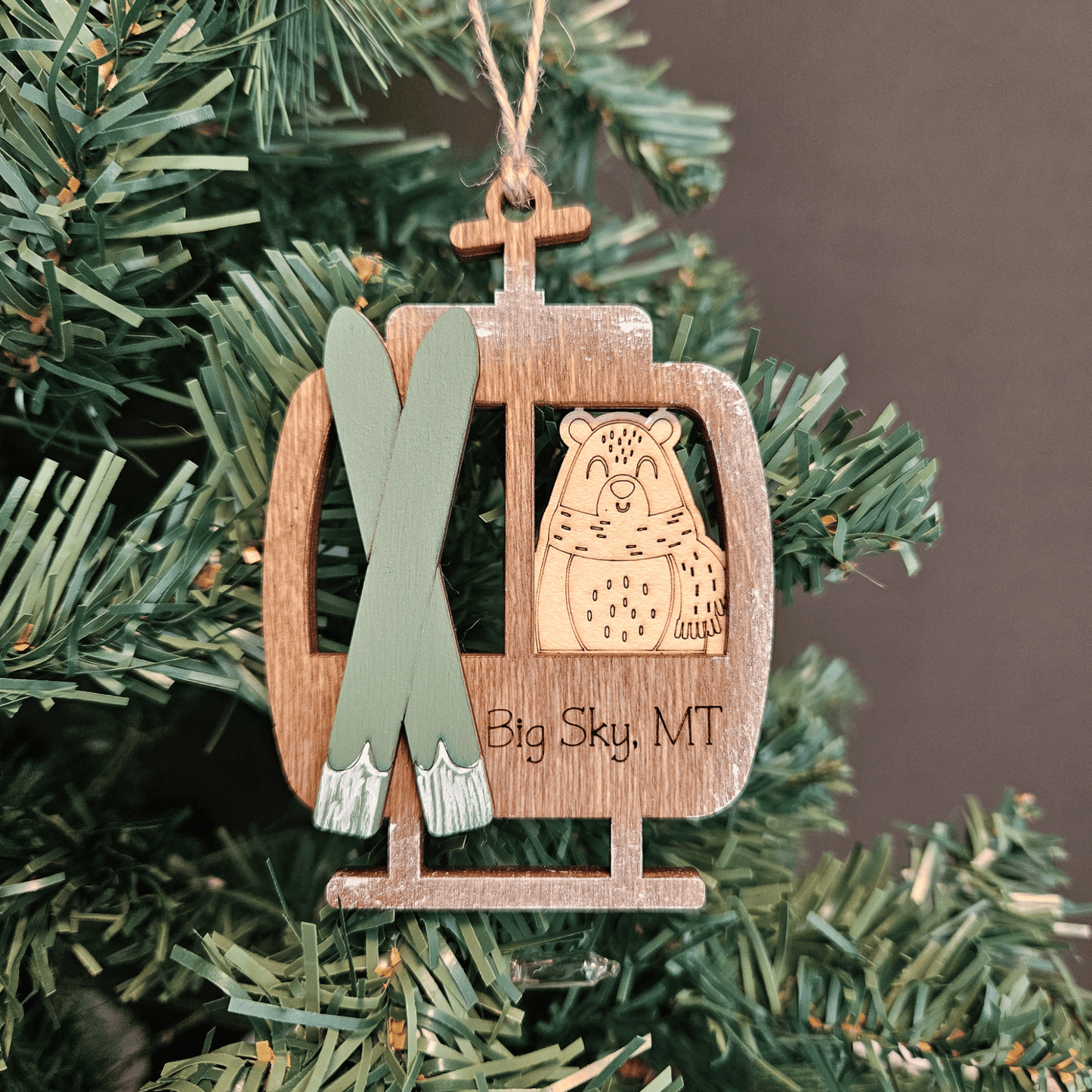 Wooden ornament with skis and bear design hanging on a Christmas tree.