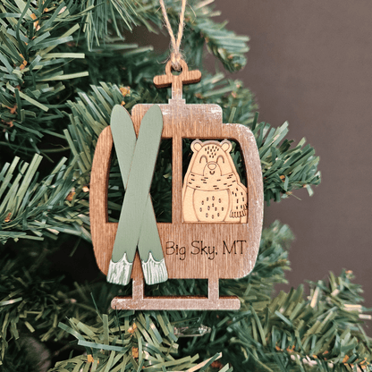 Wooden ornament with skis and bear design hanging on a Christmas tree.
