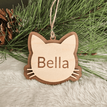 Wooden cat-shaped ornament with 'Bella' engraved, hanging on a Christmas tree.