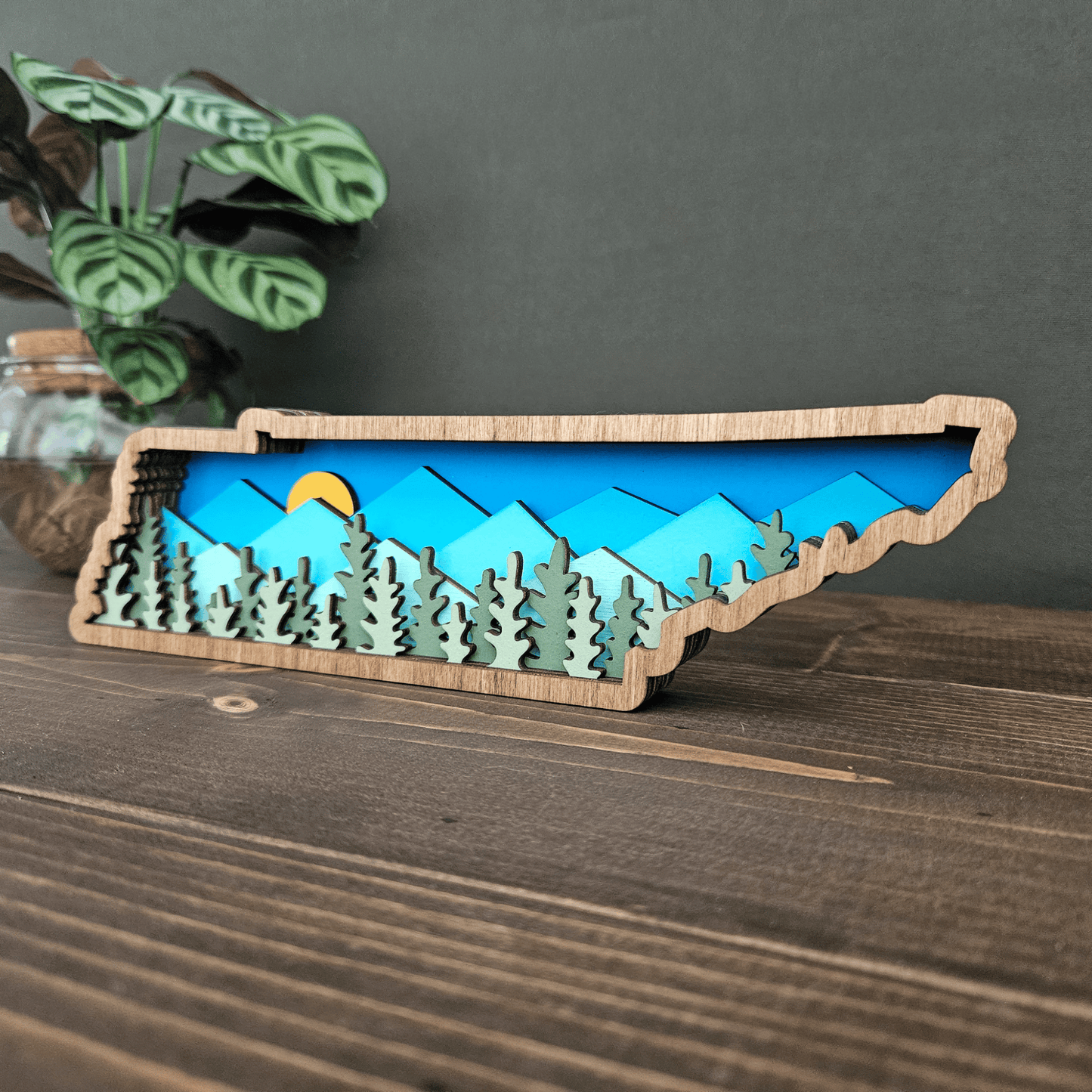 Side angle of layered Tennessee mountain scene showing sunlight over blue peaks and evergreen forest layers.