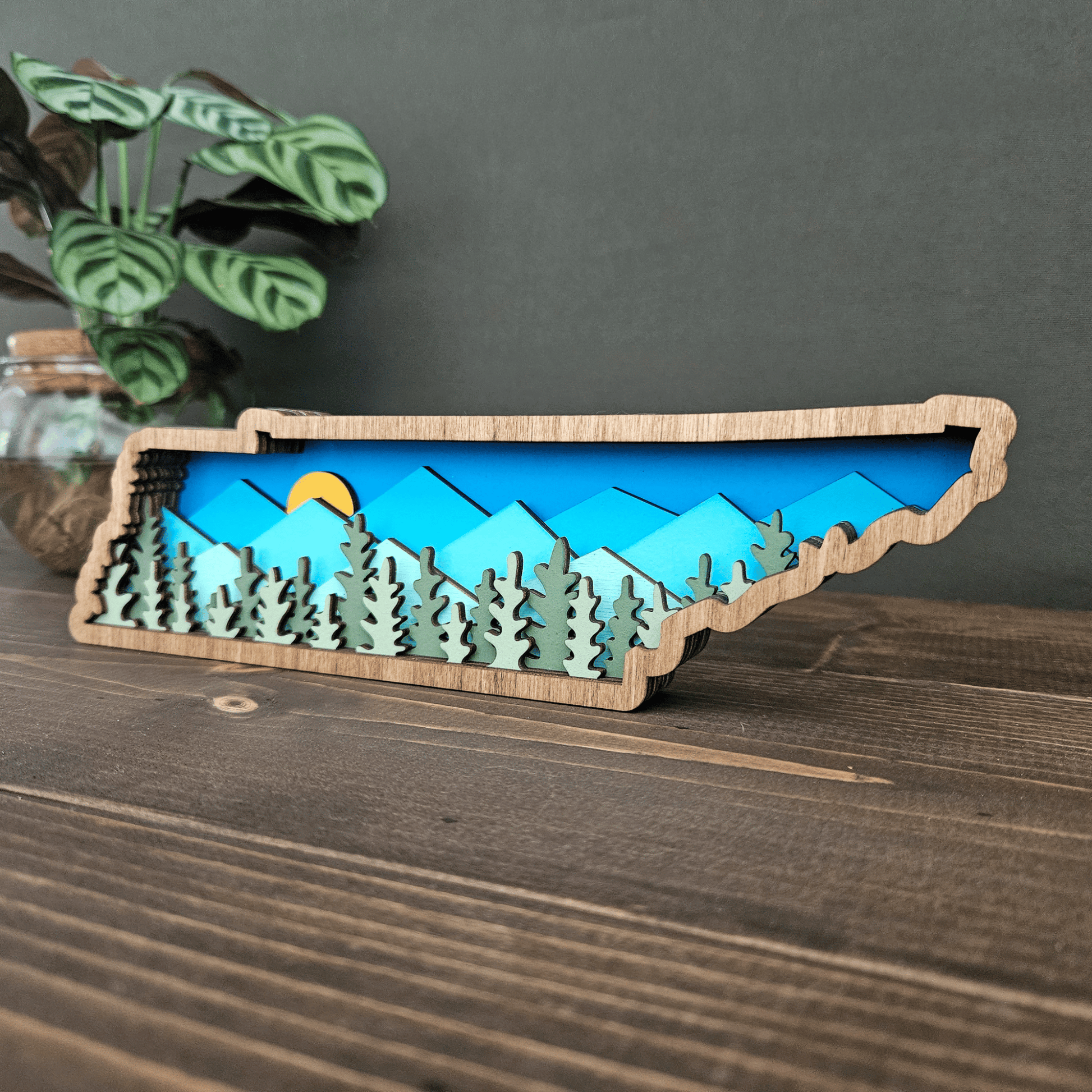 Side angle of layered Tennessee mountain scene showing sunlight over blue peaks and evergreen forest layers.