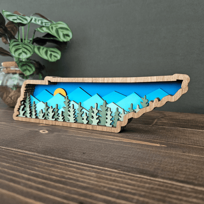 Side angle of layered Tennessee mountain scene showing sunlight over blue peaks and evergreen forest layers.