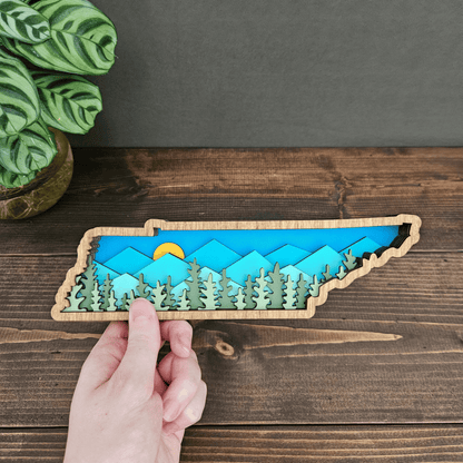 Hand holding layered Tennessee mountain wood art — small handcrafted state decor piece made by Rising Joy Creations.