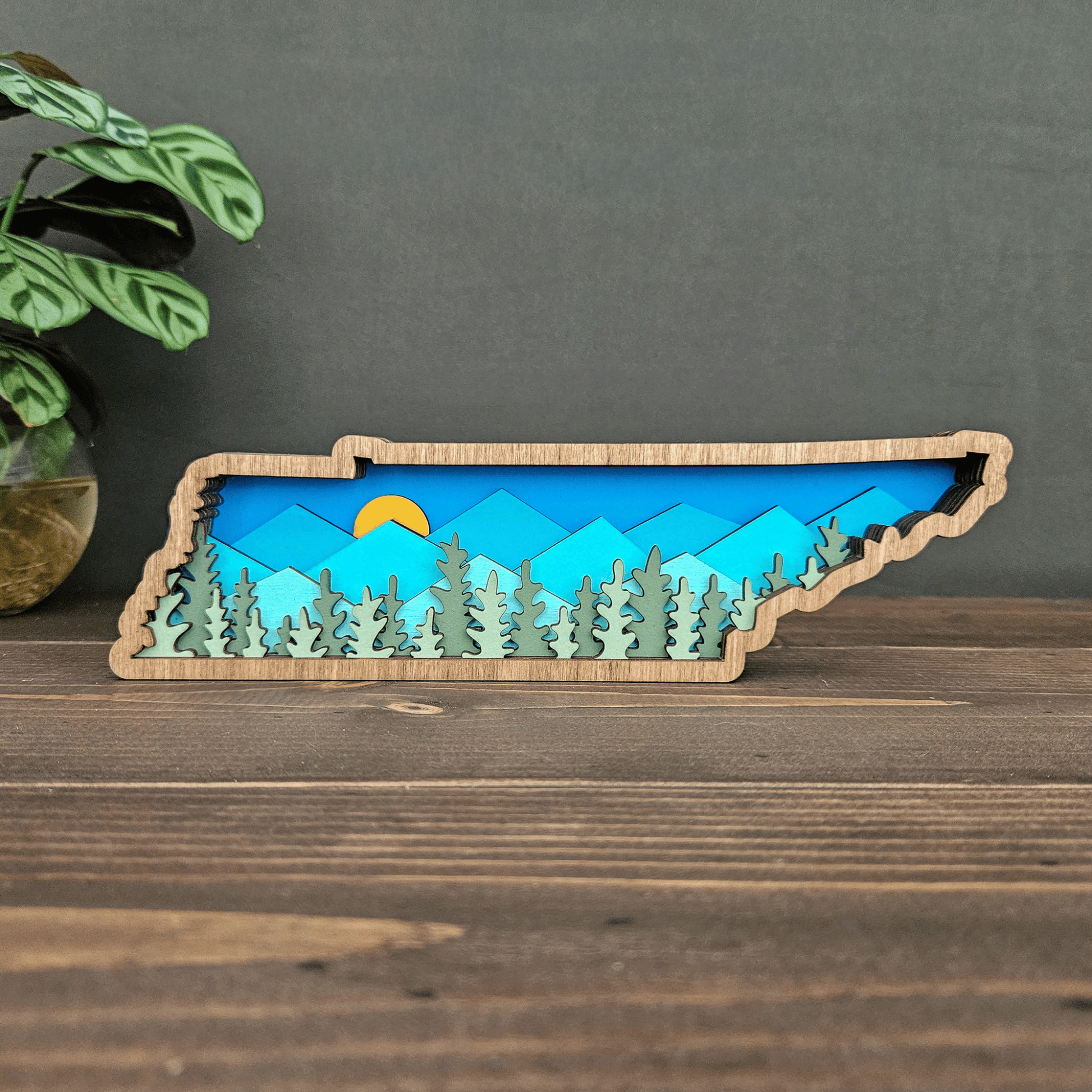 Layered Tennessee mountain art front view showing blue mountains, yellow sun, and forest cutouts — handcrafted wood decor by Rising Joy Creations.