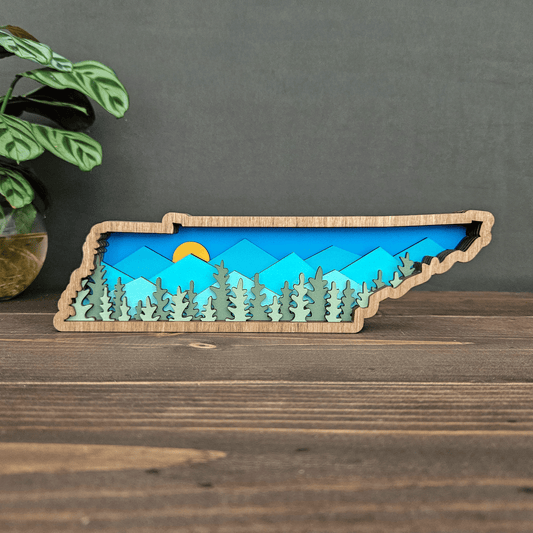 Layered Tennessee mountain art front view showing blue mountains, yellow sun, and forest cutouts — handcrafted wood decor by Rising Joy Creations.