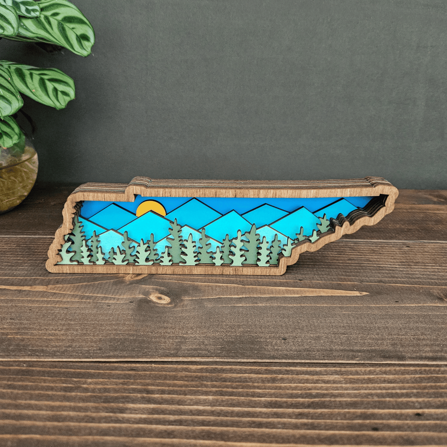 Top view of handcrafted Tennessee mountain scene in layered wood with blue and green forest design.