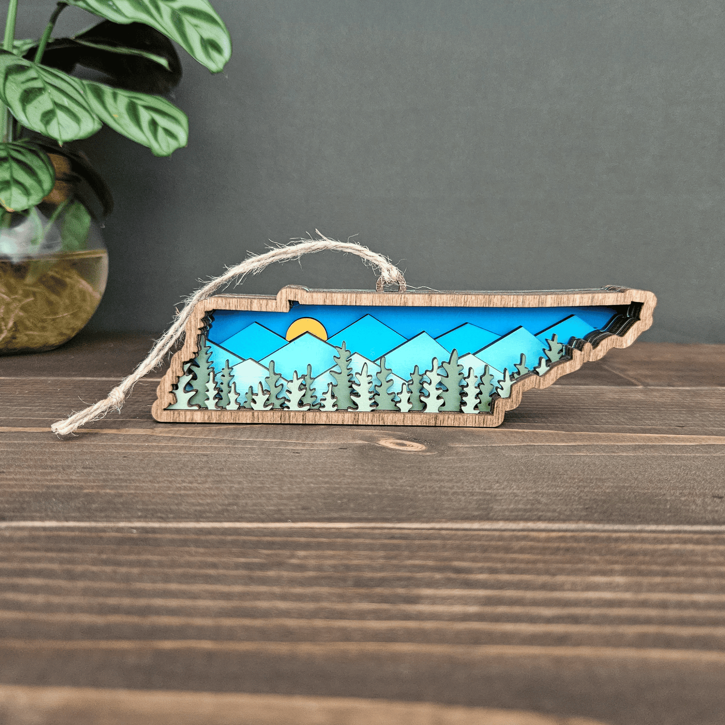Layered Tennessee mountain ornament displayed on wood surface with jute twine — handcrafted rustic state decoration.