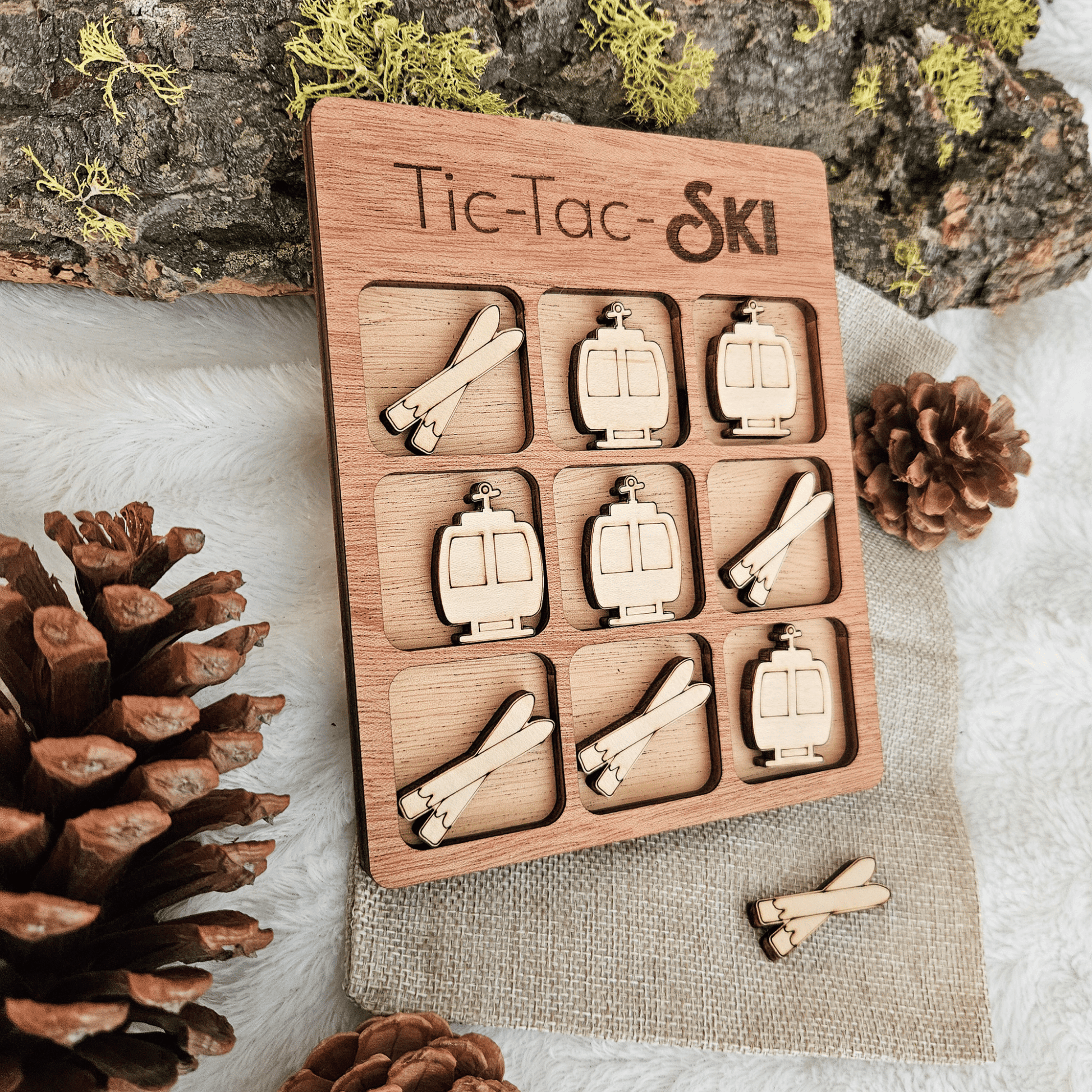 Wooden Tic-Tac-Toe game set with ski-themed pieces on a natural background