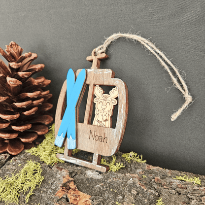Wooden ornament with a reindeer design, blue skis, and the name 'Noah' on a dark background.